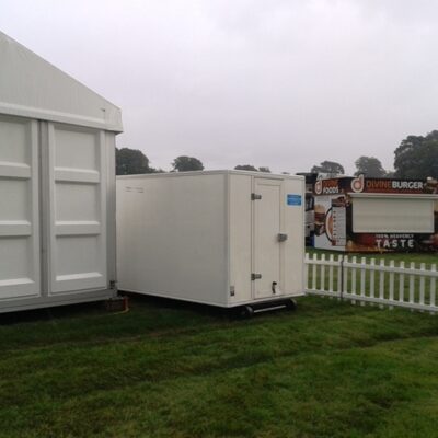 A Frostbite Refrigeration chiller trailer set up behind a busy mobile festival bar serving chilled drinks.